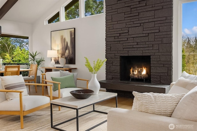 sitting room with an outdoor stone fireplace, vaulted ceiling, and wood finished floors