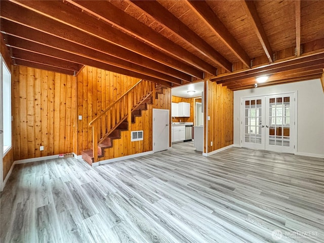 unfurnished living room featuring light wood finished floors, french doors, visible vents, and stairway