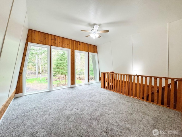 spare room with wooden walls, carpet, and a ceiling fan