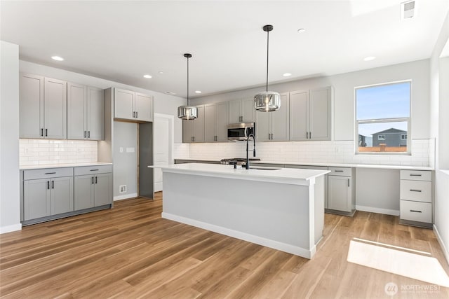 13906 178th Street Ct E Unit 62, Puyallup, WA 98374 - kitchen with stainless steel microwave, gray cabinetry, a sink, backsplash, and light countertops