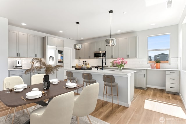 13906 178th Street Ct E Unit 62, Puyallup, WA 98374 - kitchen with stainless steel microwave, refrigerator with ice dispenser, gray cabinetry, tasteful backsplash, and light wood-style floors