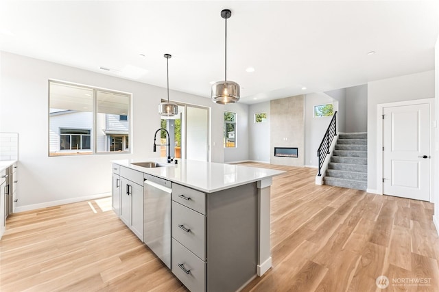 13906 178th Street Ct E Unit 62, Puyallup, WA 98374 - kitchen featuring a sink, stainless steel dishwasher, gray cabinets, a fireplace, and light wood-style flooring