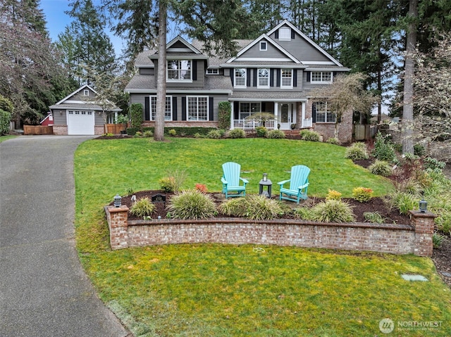 view of front of home with an outbuilding, driveway, a porch, a front yard, and a shingled roof