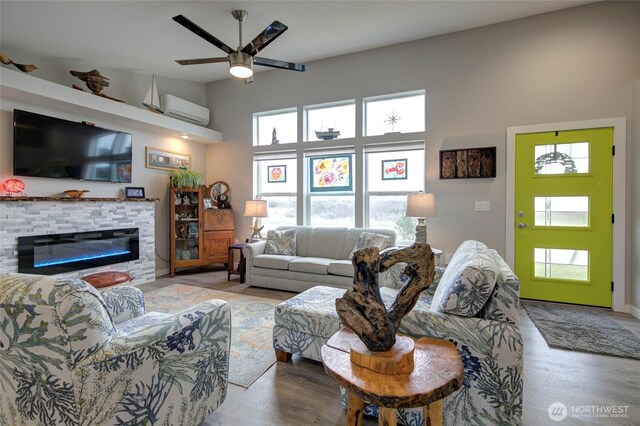 1436 Sand Pebble Ave SW, Ocean Shores, WA 98569 - living room with a stone fireplace, a wall unit AC, ceiling fan, and wood finished floors