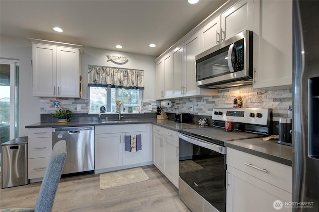 1436 Sand Pebble Ave SW, Ocean Shores, WA 98569 - kitchen featuring dark countertops, tasteful backsplash, appliances with stainless steel finishes, light wood-style floors, and a sink