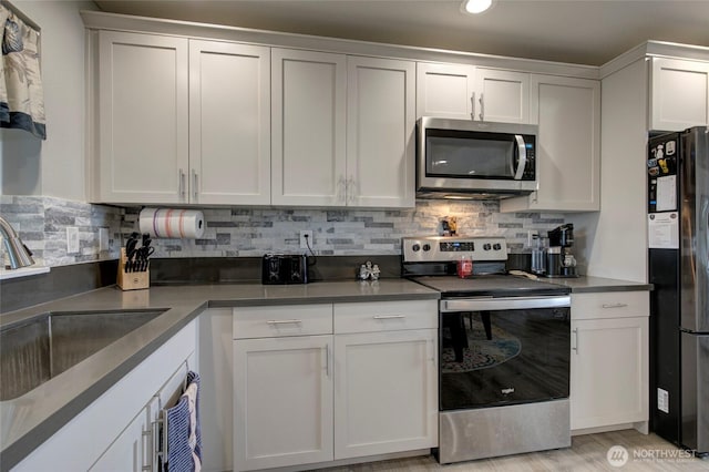 1436 Sand Pebble Ave SW, Ocean Shores, WA 98569 - kitchen with tasteful backsplash, white cabinetry, stainless steel appliances, and a sink