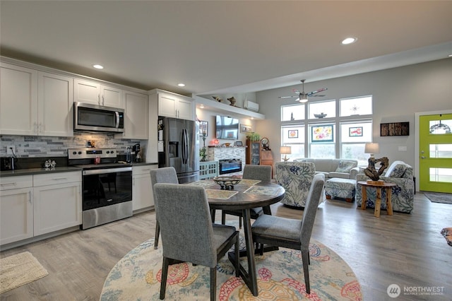 1436 Sand Pebble Ave SW, Ocean Shores, WA 98569 - dining space featuring a glass covered fireplace, recessed lighting, light wood-style floors, and ceiling fan