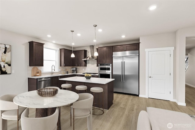 10591 135th Ave NE Unit 24, Kirkland, WA 98033 - kitchen featuring stainless steel appliances, wall chimney range hood, a sink, dark brown cabinetry, and a center island