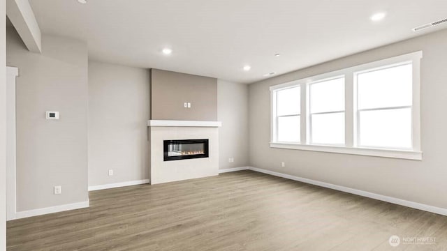 10591 135th Ave NE Unit 24, Kirkland, WA 98033 - unfurnished living room featuring wood finished floors, a glass covered fireplace, baseboards, and recessed lighting