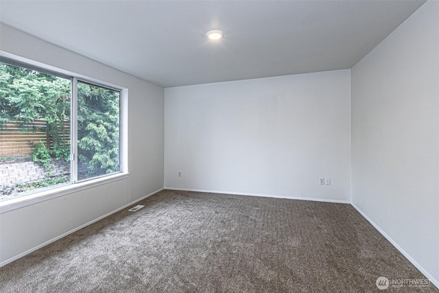 carpeted spare room featuring visible vents and baseboards