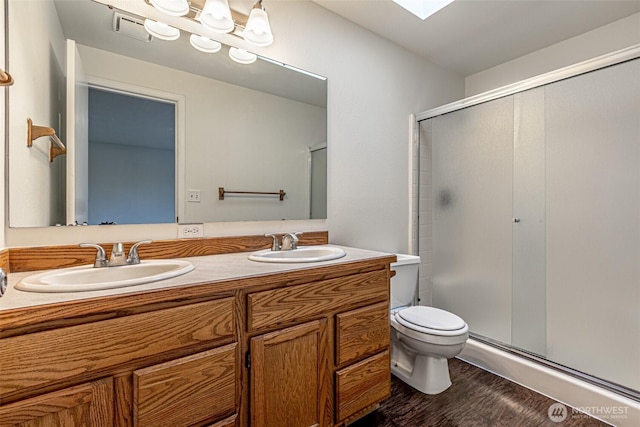 full bath with a sink, a shower stall, toilet, and double vanity