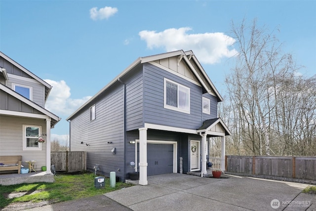 view of side of property with board and batten siding, fence, driveway, and a garage