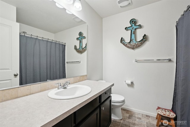 full bath featuring baseboards, vanity, toilet, and stone finish flooring