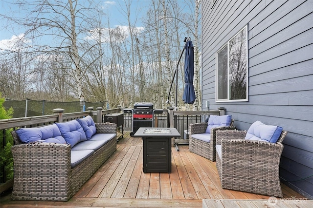 wooden terrace featuring area for grilling and an outdoor living space with a fire pit