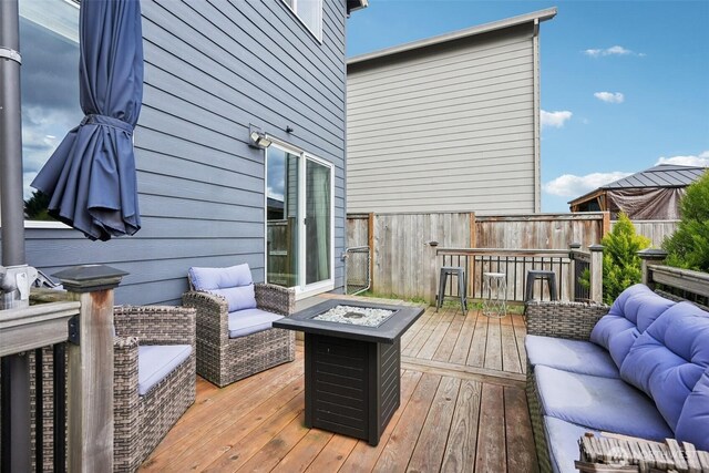 deck featuring an outdoor living space with a fire pit
