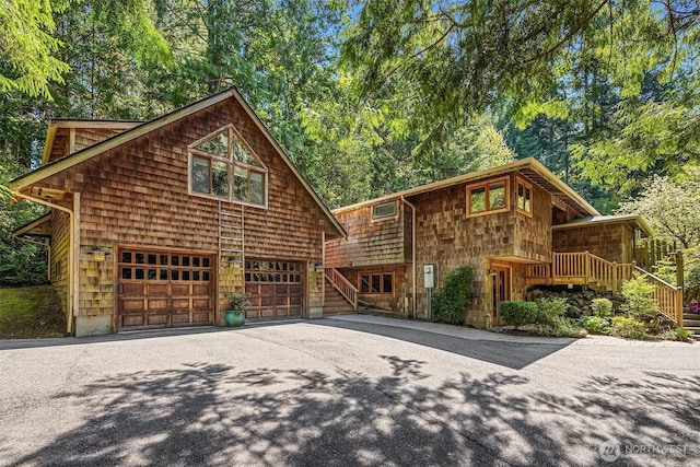 view of front of property featuring an attached garage, stairs, and aphalt driveway