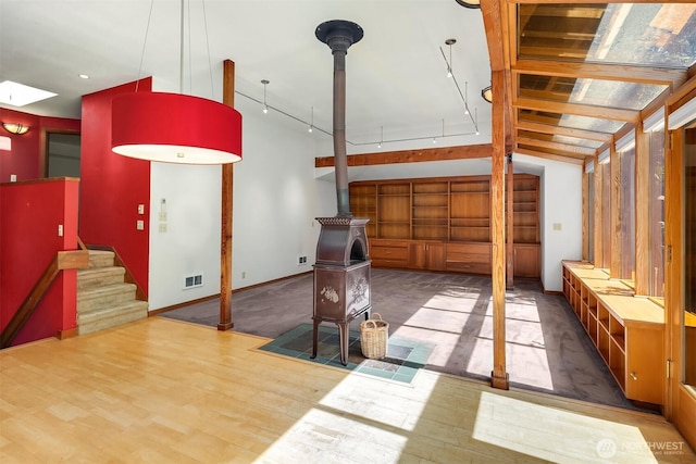 interior space with visible vents, a wood stove, baseboards, and stairway