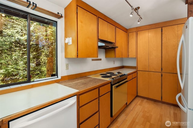 kitchen featuring brown cabinets, white appliances, light countertops, light wood-type flooring, and under cabinet range hood