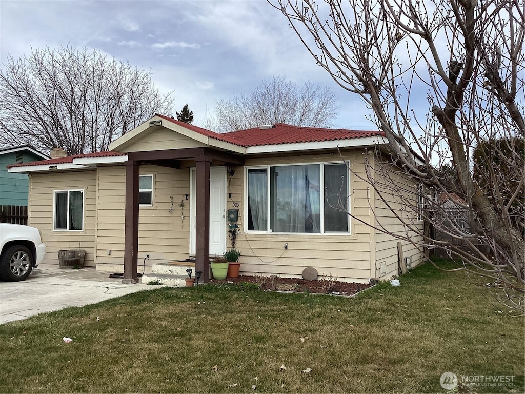 bungalow-style house featuring a front lawn, a patio area, and metal roof