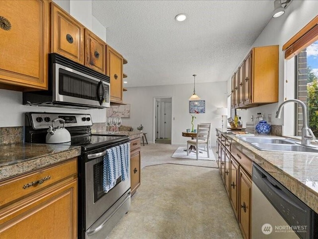 3616 SW 325th St, Federal Way, WA 98023 - kitchen featuring stainless steel appliances, a sink, brown cabinetry, a textured ceiling, and decorative light fixtures