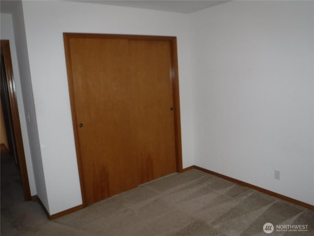unfurnished bedroom featuring a closet, baseboards, and carpet flooring