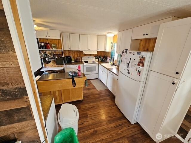 6505 Fawn Ln Unit 4, Long Beach, WA 98631 - kitchen featuring white appliances, under cabinet range hood, a sink, dark wood-style floors, and white cabinets