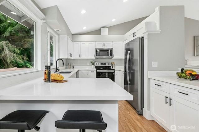 17406 Redhawk Dr, Arlington, WA 98223 - kitchen featuring appliances with stainless steel finishes, a sink, vaulted ceiling, a peninsula, and white cabinets