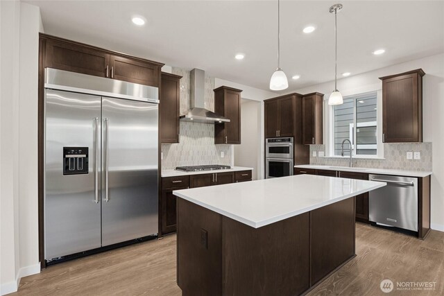 11579 SE 84th St Unit 46, Newcastle, WA 98056 - kitchen with stainless steel appliances, wall chimney range hood, dark brown cabinets, light wood-style floors, and decorative backsplash