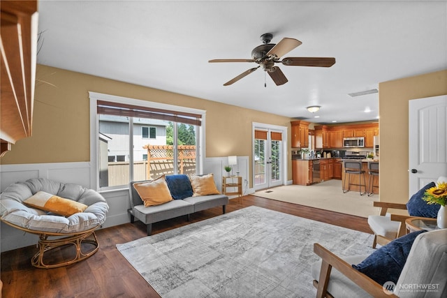 1625 185th Street Ct E, Spanaway, WA 98387 - living room featuring a ceiling fan, light wood-style floors, french doors, and a wainscoted wall