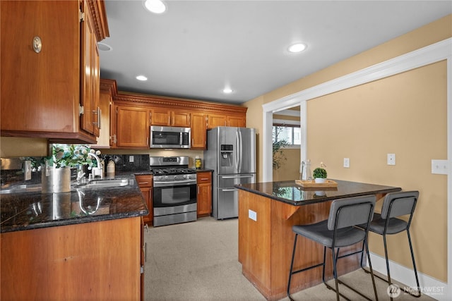 1625 185th Street Ct E, Spanaway, WA 98387 - kitchen with appliances with stainless steel finishes, a breakfast bar area, brown cabinetry, light colored carpet, and recessed lighting