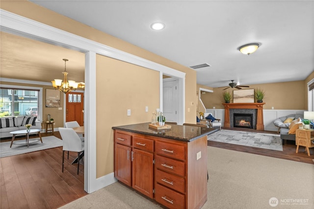 1625 185th Street Ct E, Spanaway, WA 98387 - kitchen featuring ceiling fan, a chandelier, a glass covered fireplace, wood finished floors, and dark stone countertops