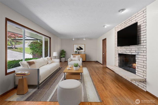 1918 SE Maple Dr, Chehalis, WA 98532 - living room featuring a brick fireplace, wood finished floors, and a textured ceiling