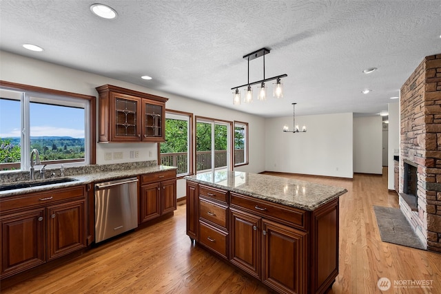 1918 SE Maple Dr, Chehalis, WA 98532 - kitchen featuring dishwasher, a sink, light wood-style floors, a textured ceiling, and light stone counters