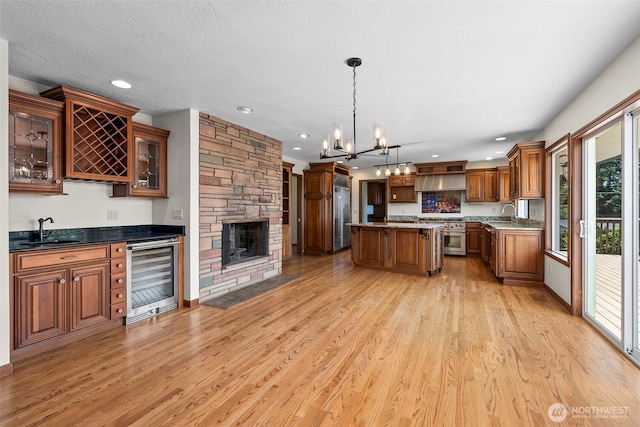 1918 SE Maple Dr, Chehalis, WA 98532 - kitchen with wine cooler, a sink, brown cabinetry, light wood-type flooring, and premium appliances
