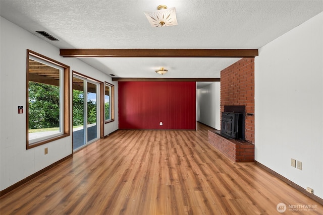 1918 SE Maple Dr, Chehalis, WA 98532 - unfurnished living room with a textured ceiling, beamed ceiling, wood finished floors, a fireplace, and baseboards
