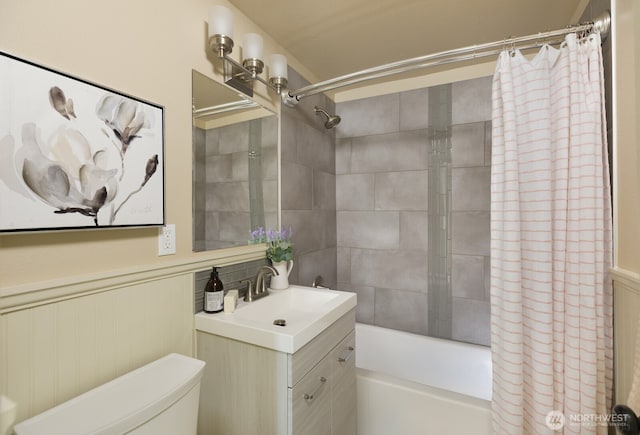 full bath featuring a wainscoted wall, toilet, shower / bath combination with curtain, and vanity