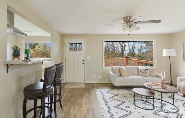 living room featuring baseboards, ceiling fan, and light wood-style flooring