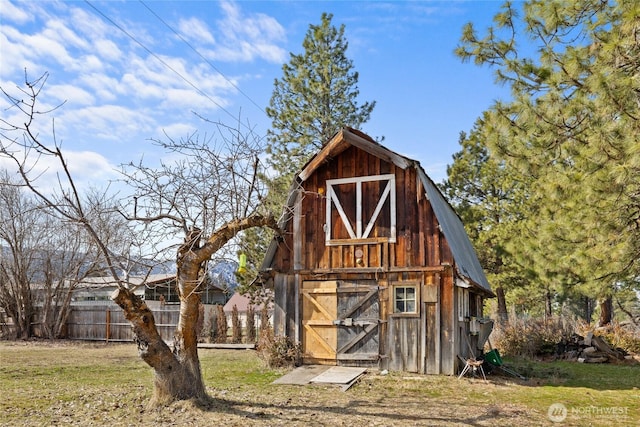 view of barn with a lawn and fence
