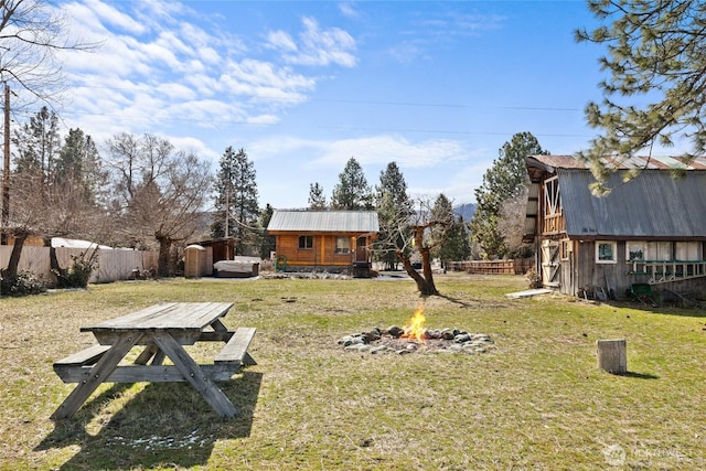 view of yard with an outdoor structure, a fire pit, and fence