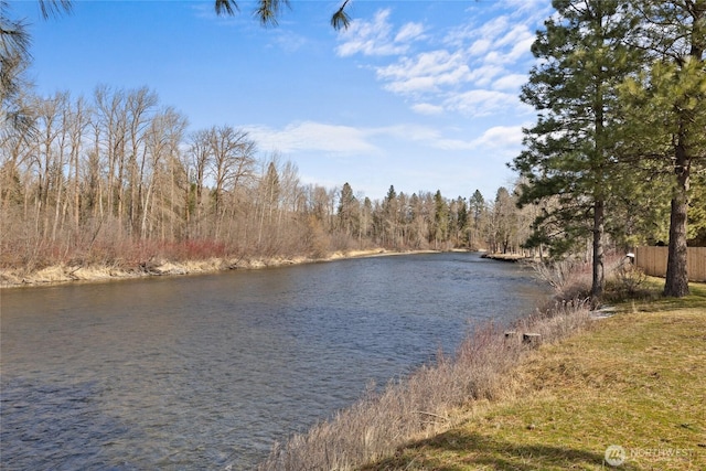 water view featuring a forest view and fence
