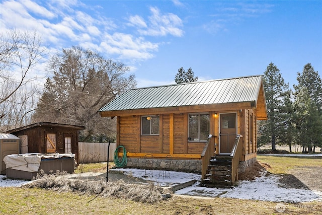 view of front of house featuring an outbuilding, fence, and metal roof