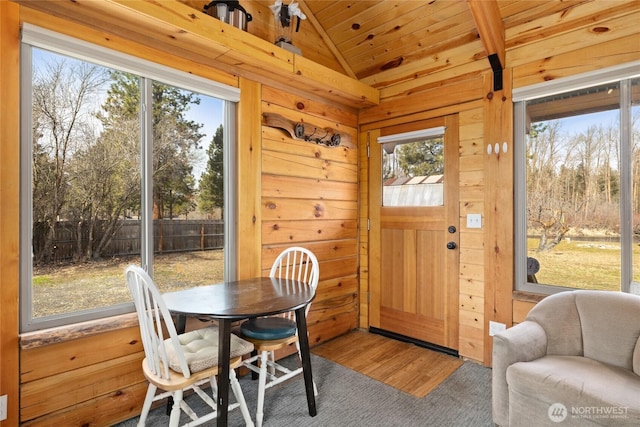 dining space featuring wooden walls, wooden ceiling, lofted ceiling, and wood finished floors