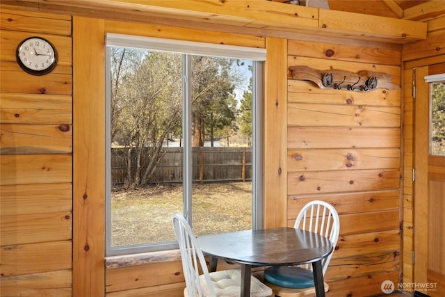 dining area with wooden walls and a healthy amount of sunlight
