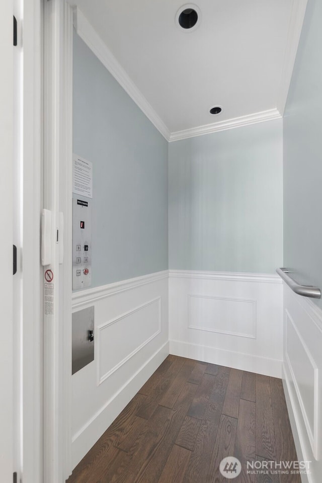 spare room featuring dark wood finished floors, wainscoting, crown molding, and elevator