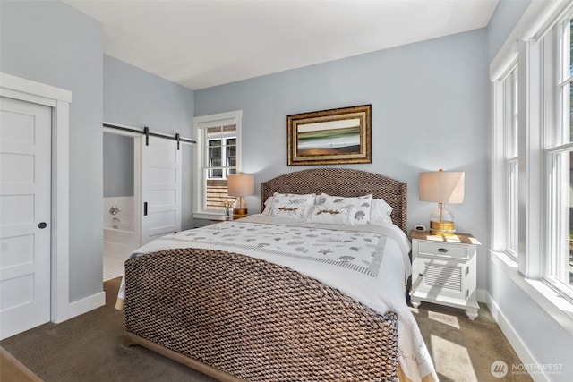 carpeted bedroom with a barn door and baseboards