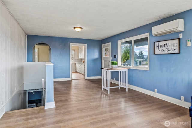 160 Maple St, Cathlamet, WA 98612 - interior space with a wall mounted air conditioner, baseboards, arched walkways, and wood finished floors