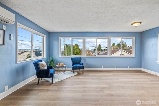 160 Maple St, Cathlamet, WA 98612 - sitting room featuring wood finished floors, baseboards, a wall mounted air conditioner, and a textured ceiling