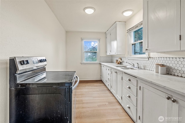 160 Maple St, Cathlamet, WA 98612 - kitchen with tasteful backsplash, stainless steel range with electric stovetop, light wood-style floors, white cabinets, and a sink