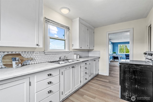 160 Maple St, Cathlamet, WA 98612 - kitchen featuring a sink, decorative backsplash, white cabinets, and light wood-style flooring