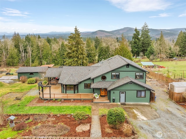 21401 161st Ave E, Graham, WA 98338 - view of front of property featuring a deck with mountain view, driveway, a view of trees, fence, and a shingled roof